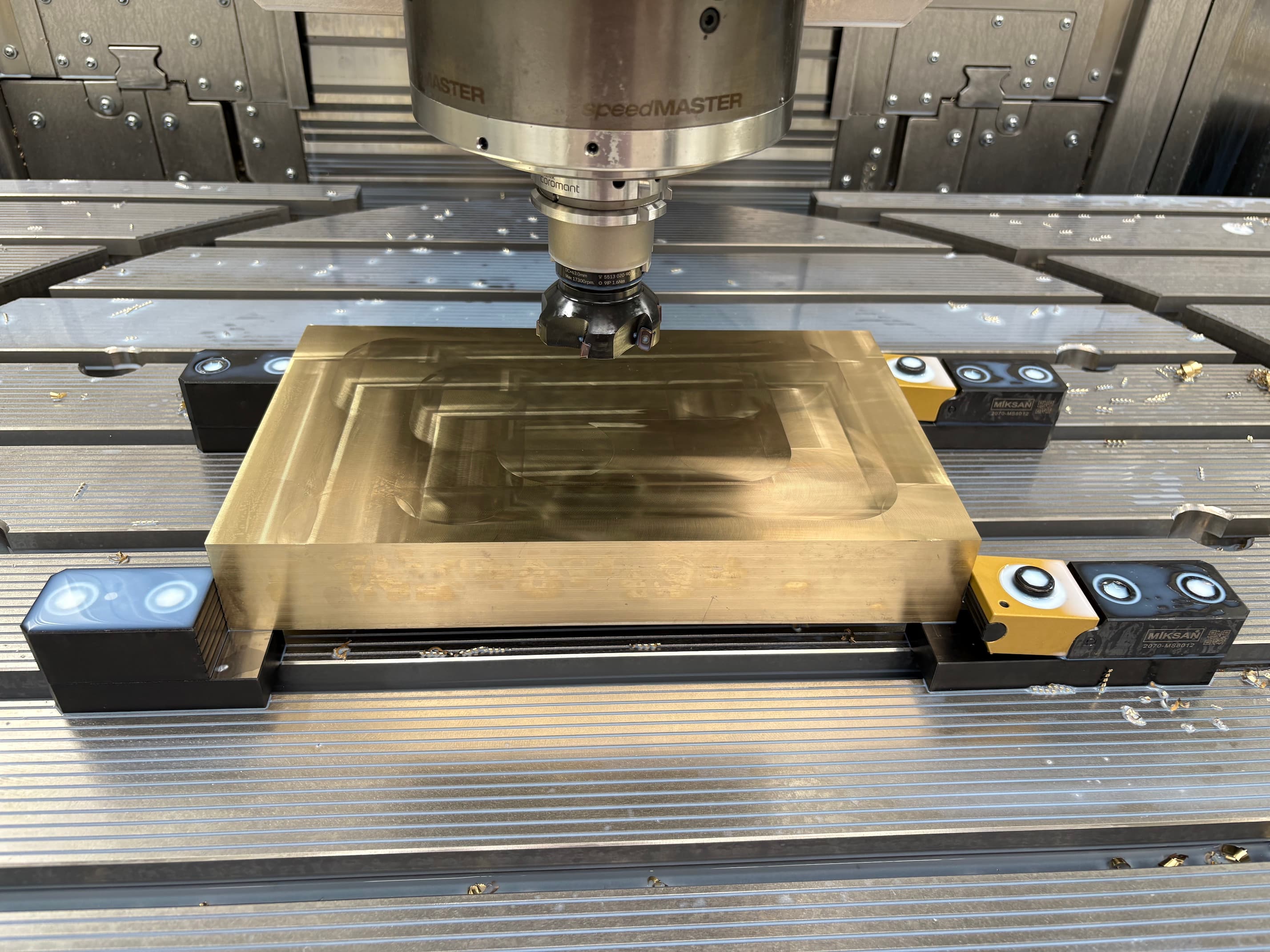A golden metal block inside a CNC machine