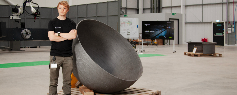 A man standing next to an additively manufactured metal hemisphere