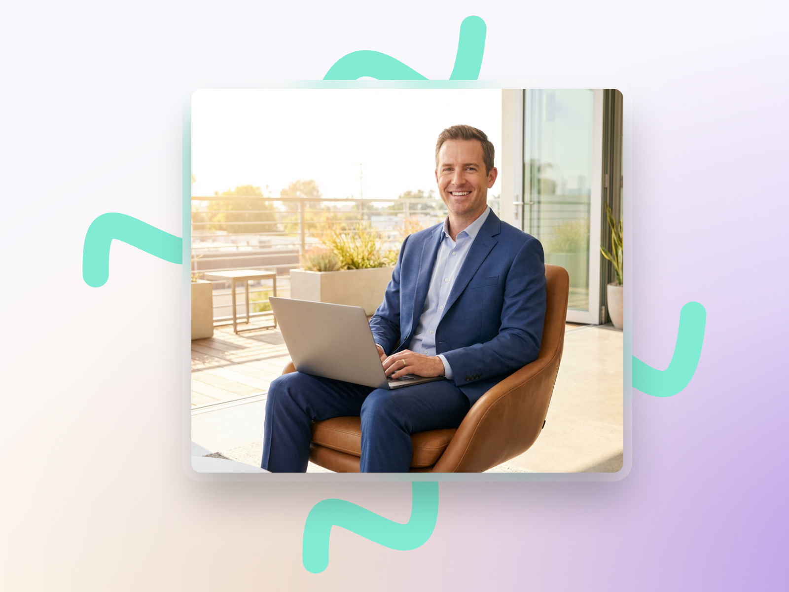 A man in a suit sits on a chair, working on a laptop with a happy expression
