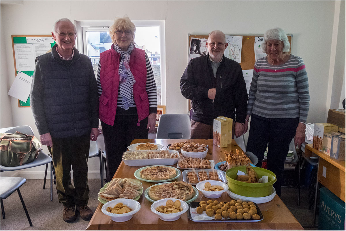 Four parishioners standing behind a table of food at a parish event