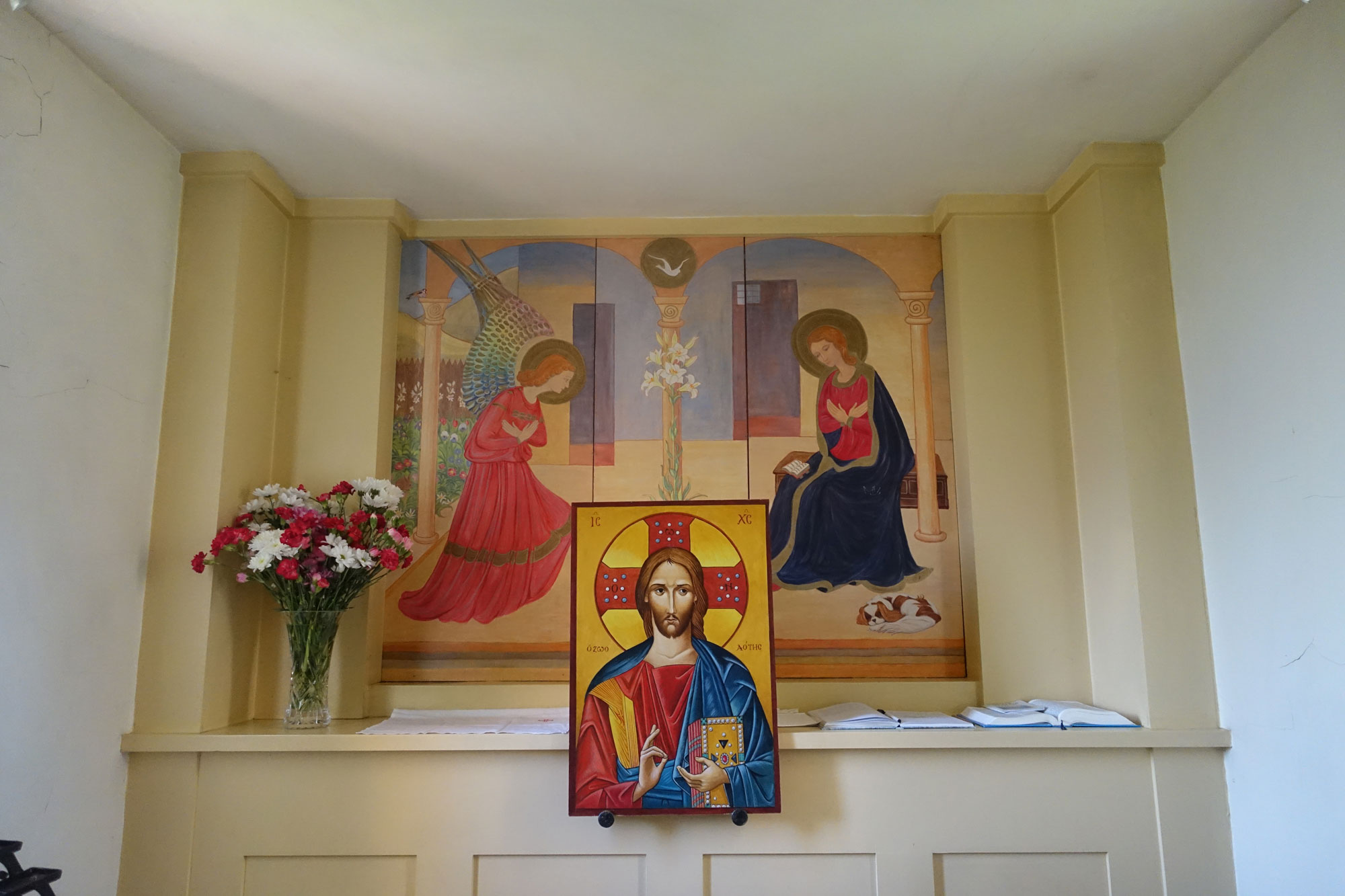 A side altar at Holy Cross with a painting of the Annunciation above an icon of Christ